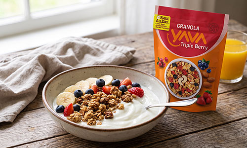Semangkuk yoghurt dengan topping Granola YAVA dan potongan buah segar, disajikan di samping kemasan granola.
