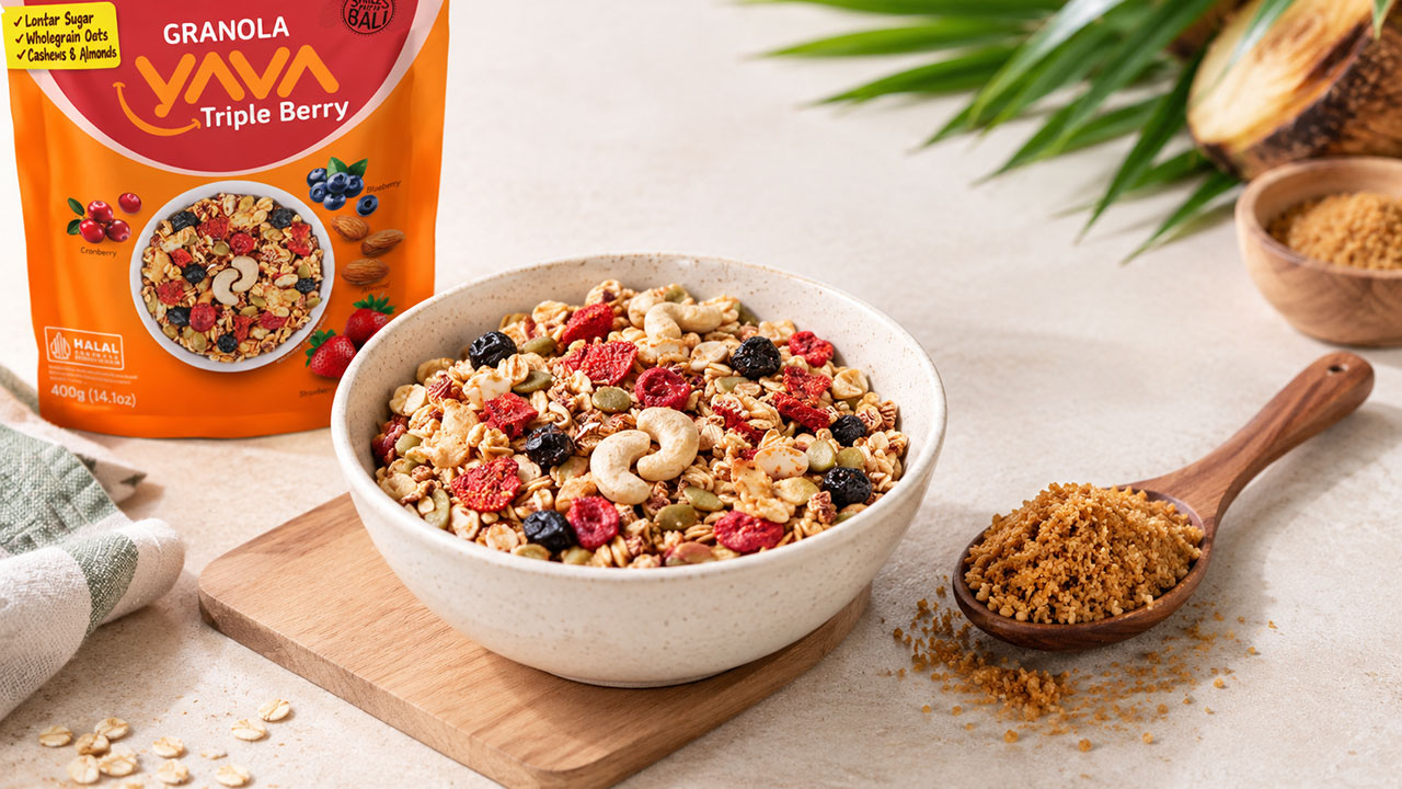 Granola YAVA dan Gula Lontar Semangkuk Granola YAVA di samping sendok berisi gula lontar.